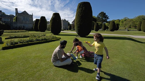 Family in the garden at Lanhydrock, Cornwall with children playing and adults seated